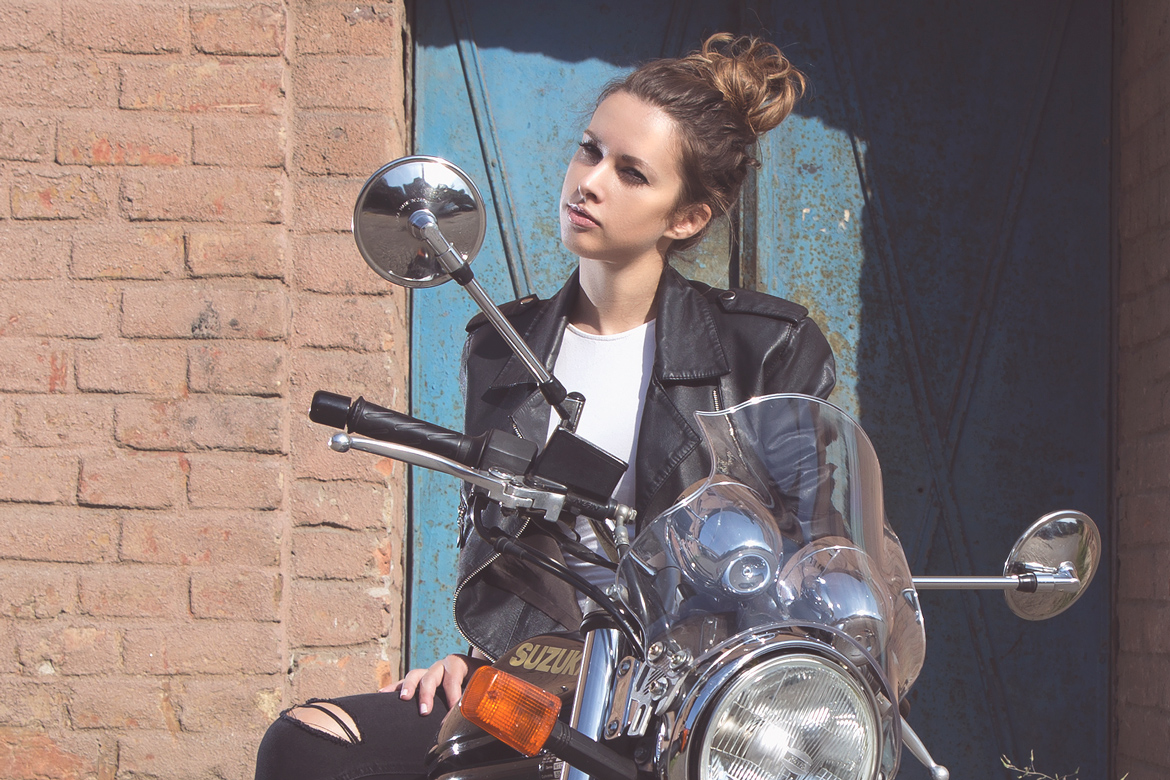 Girl on a motorbike with blue doors behind