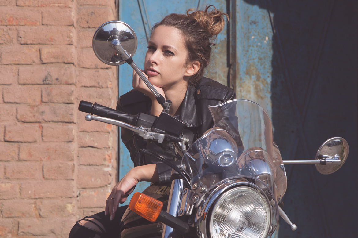 Hazy portrait of a girl on a motorbike with blue doors behind